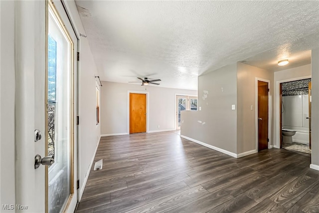 interior space featuring visible vents, dark wood-style flooring, baseboards, a textured ceiling, and a ceiling fan