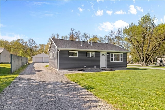 view of front of property featuring a detached garage, an outbuilding, roof with shingles, and a front lawn