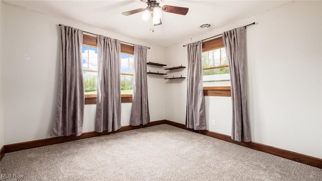 carpeted spare room with baseboards, ceiling fan, and visible vents