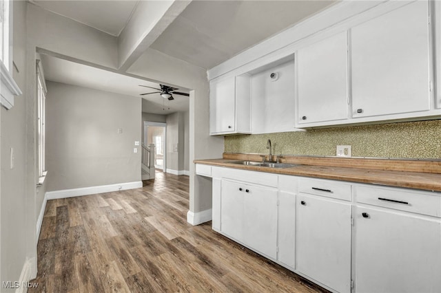 kitchen featuring decorative backsplash, wood finished floors, ceiling fan, white cabinetry, and a sink