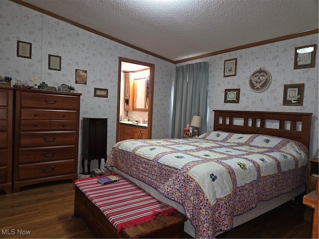 bedroom with crown molding, a textured ceiling, wallpapered walls, ensuite bathroom, and dark wood-style floors