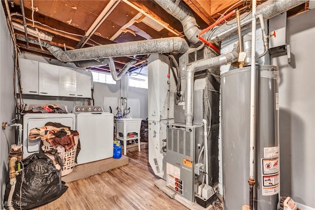 basement featuring visible vents, wood finished floors, a sink, water heater, and separate washer and dryer