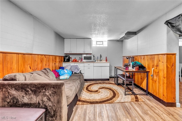 interior space with concrete block wall, a textured ceiling, and light wood finished floors