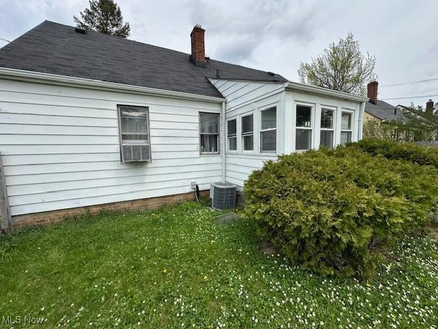 back of house with a yard, central AC, and a chimney