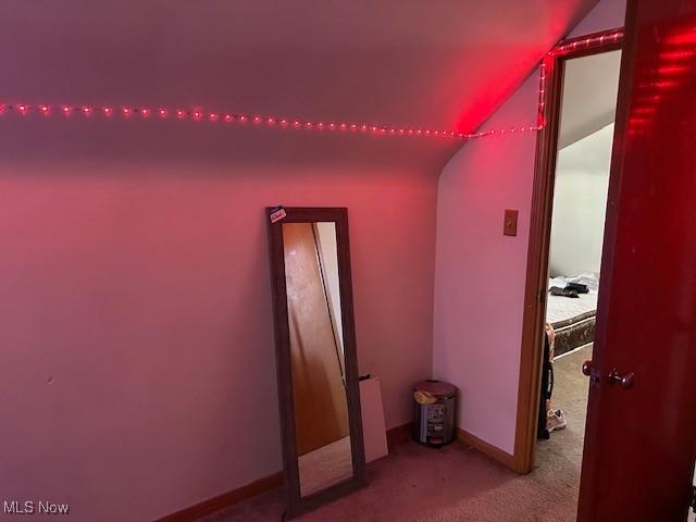 interior space with baseboards, carpet flooring, and lofted ceiling