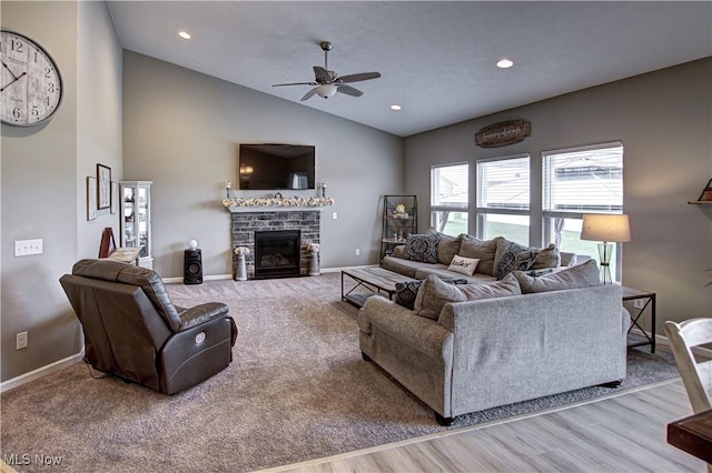 living area with ceiling fan, baseboards, lofted ceiling, a glass covered fireplace, and carpet