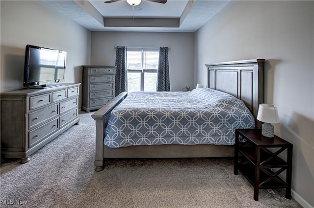 bedroom featuring a raised ceiling, ceiling fan, light carpet, and baseboards