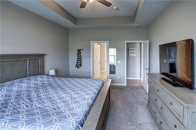 carpeted bedroom with baseboards, a raised ceiling, ceiling fan, and visible vents