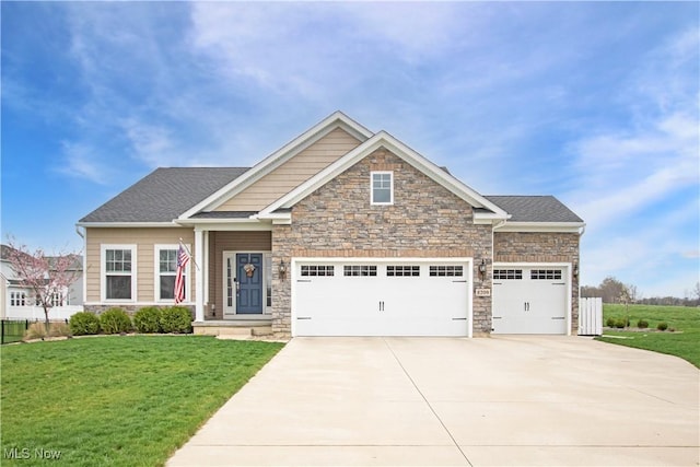 craftsman house featuring driveway, a front yard, fence, an attached garage, and stone siding