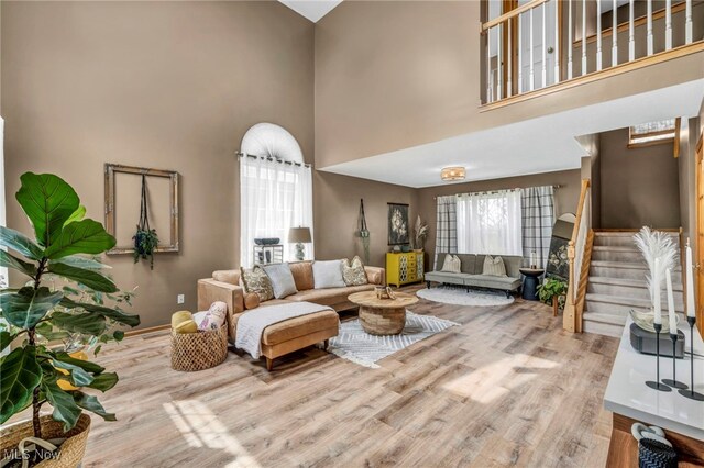 living area with wood finished floors, stairs, and a high ceiling