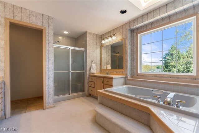 bathroom featuring a skylight, a shower stall, a bath, and vanity