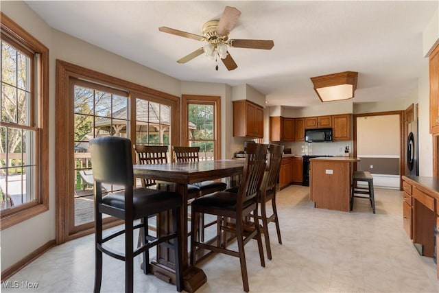 dining room featuring baseboards, a ceiling fan, light floors, and a healthy amount of sunlight