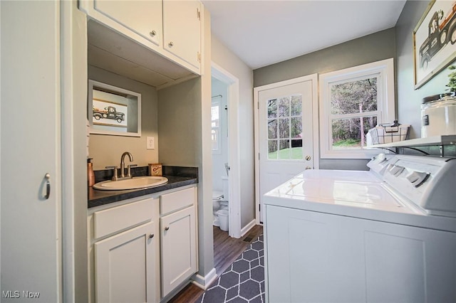 clothes washing area featuring baseboards, separate washer and dryer, a sink, cabinet space, and water heater