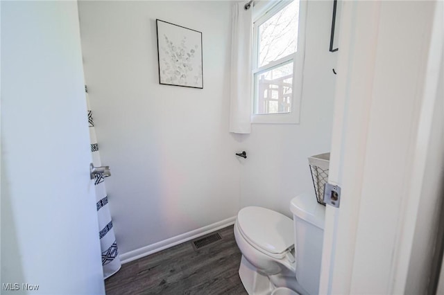 bathroom with baseboards, toilet, wood finished floors, and visible vents