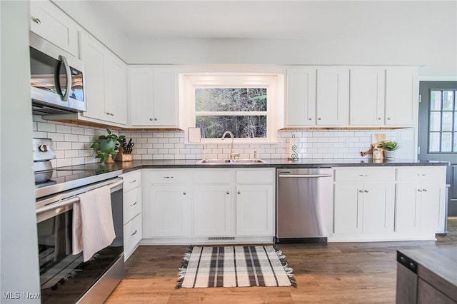 kitchen featuring stainless steel appliances, white cabinetry, a sink, and tasteful backsplash