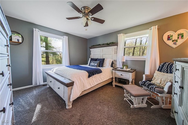bedroom featuring a ceiling fan, baseboards, multiple windows, and dark carpet