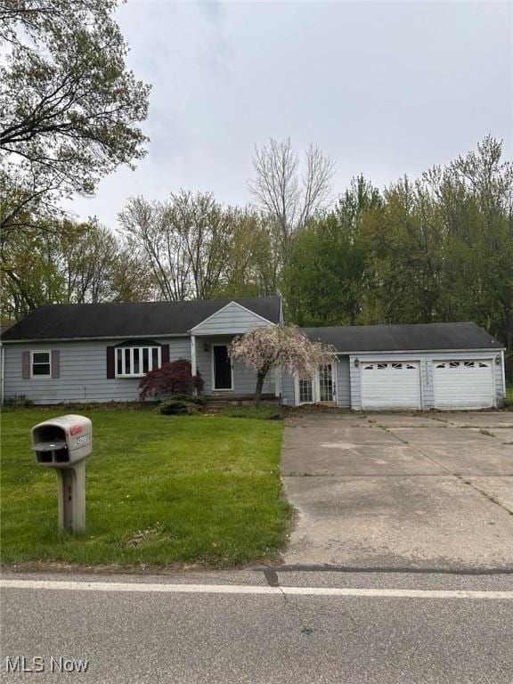 single story home with concrete driveway, an attached garage, and a front lawn
