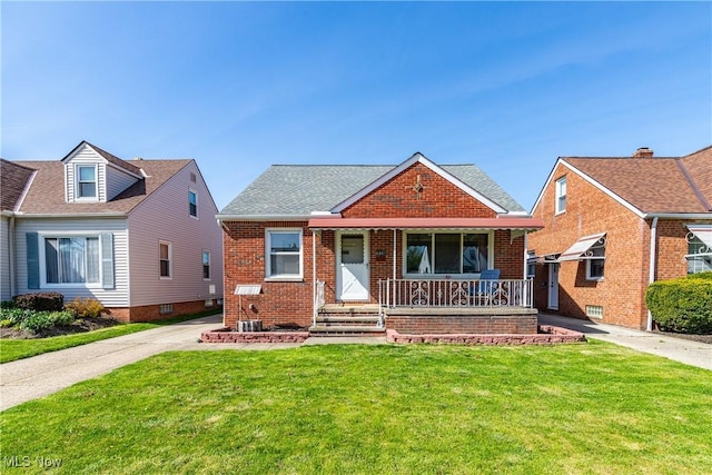 bungalow with brick siding, roof with shingles, a front yard, and a porch