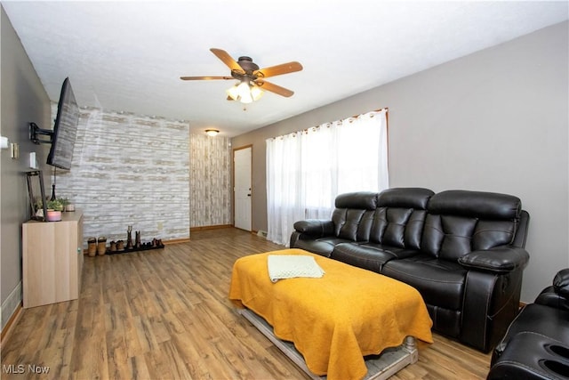 living area featuring baseboards, a ceiling fan, and wood finished floors