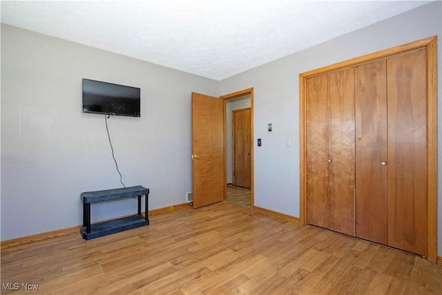 unfurnished bedroom featuring a closet, baseboards, and light wood-type flooring