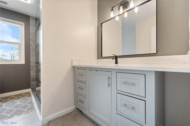 full bathroom with vanity, baseboards, and a shower stall