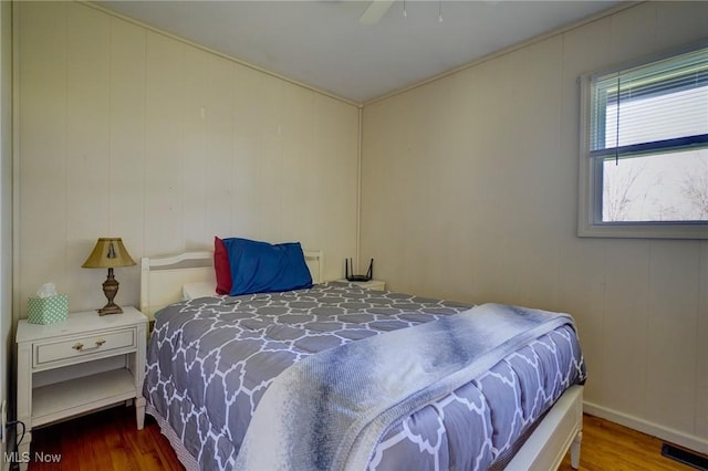 bedroom with a ceiling fan, wood finished floors, and visible vents
