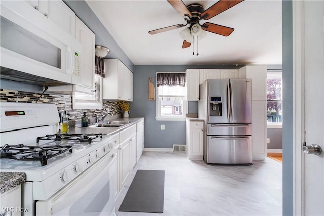 kitchen with white appliances, a ceiling fan, a wealth of natural light, and a sink