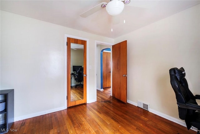 unfurnished office with visible vents, a ceiling fan, baseboards, and hardwood / wood-style flooring