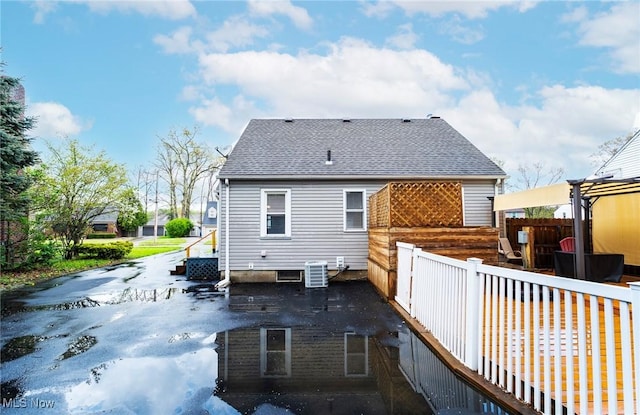 rear view of property featuring fence and a shingled roof