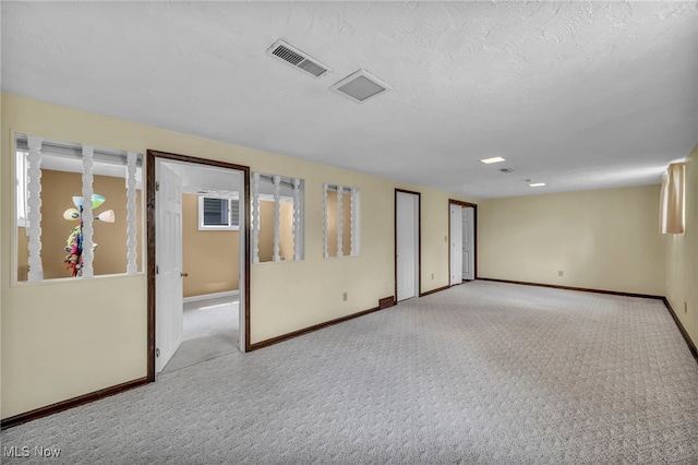 carpeted spare room featuring baseboards and visible vents