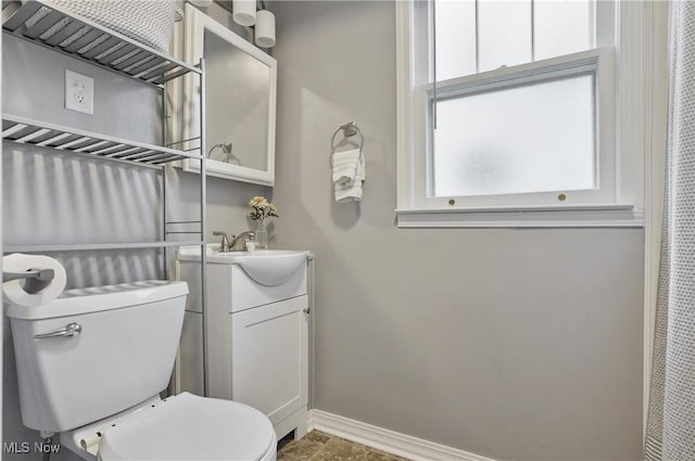 bathroom featuring baseboards, toilet, and vanity