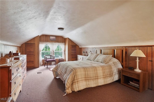 carpeted bedroom featuring visible vents, lofted ceiling, and wooden walls