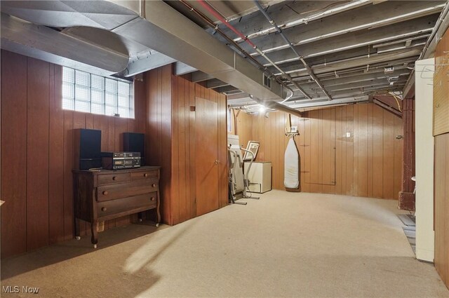 basement featuring wooden walls, carpet flooring, and washing machine and clothes dryer