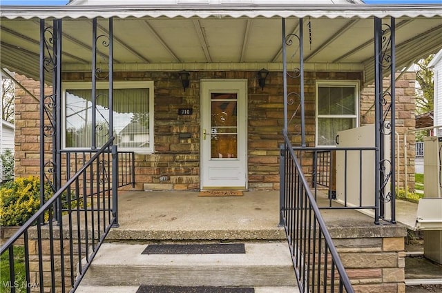property entrance featuring covered porch and stone siding