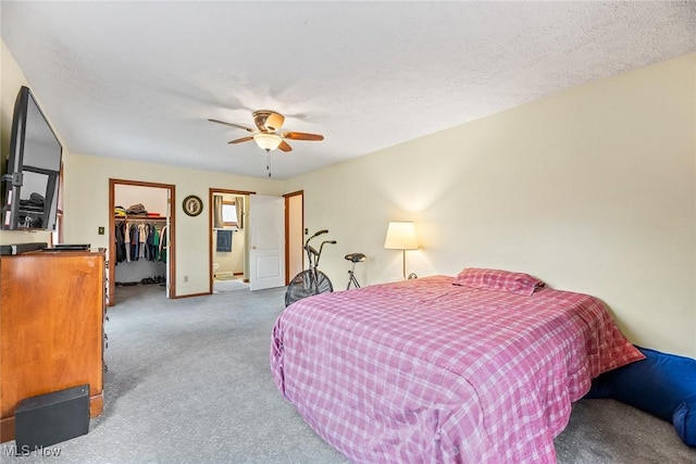 bedroom with carpet flooring, ceiling fan, a walk in closet, baseboards, and a closet
