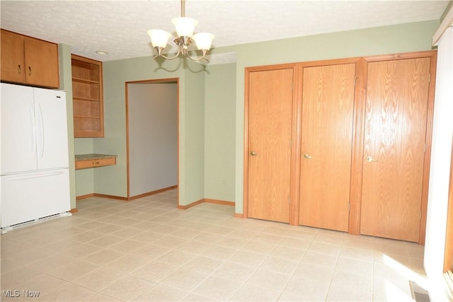 unfurnished dining area featuring a textured ceiling, a notable chandelier, baseboards, and visible vents