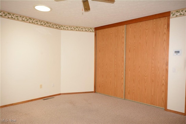 carpeted spare room with ceiling fan, visible vents, and baseboards