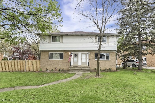 view of front of house featuring fence, a front lawn, and brick siding