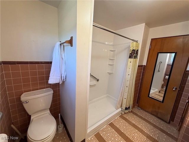 full bathroom featuring tile walls, wainscoting, and a stall shower