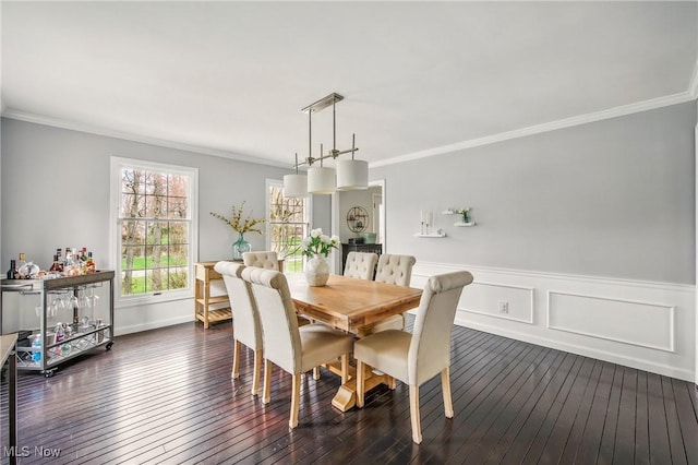 dining space with crown molding, a wainscoted wall, and dark wood-style floors