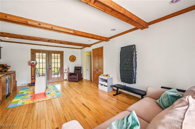 living area featuring ornamental molding, light wood-style flooring, french doors, and beam ceiling