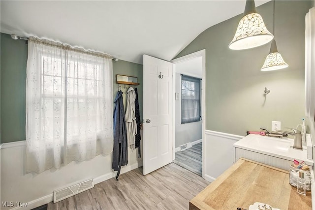 bathroom featuring baseboards, visible vents, wood finished floors, and vaulted ceiling