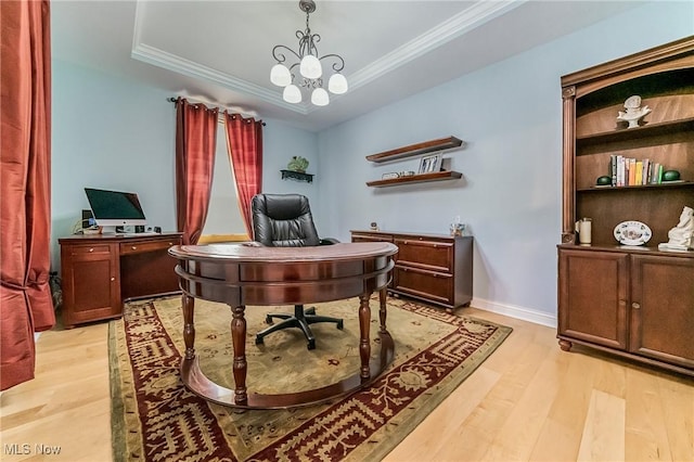 office space with a tray ceiling, ornamental molding, and light wood-type flooring