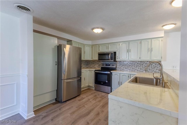 3050 Latimer Ave, Ashtabula, OH 44004 - kitchen with appliances with stainless steel finishes, a sink, backsplash, light countertops, and light wood-style flooring