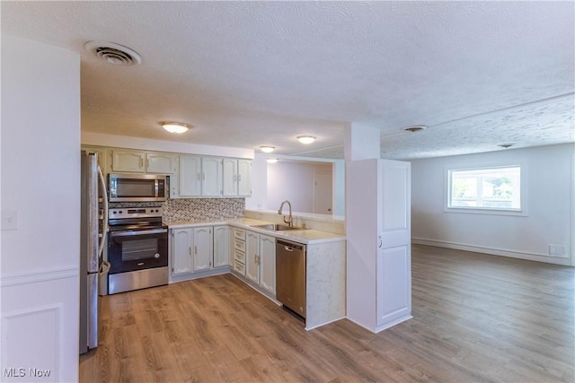 3050 Latimer Ave, Ashtabula, OH 44004 - kitchen with appliances with stainless steel finishes, a sink, light countertops, light wood-style flooring, and a textured ceiling
