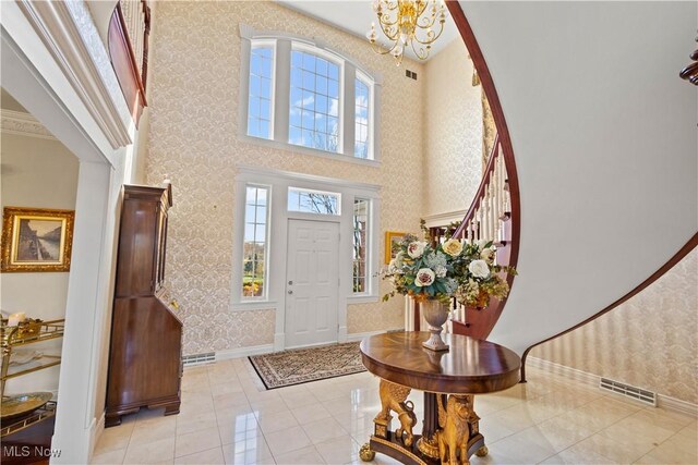 entryway with visible vents, baseboards, a high ceiling, wallpapered walls, and a notable chandelier
