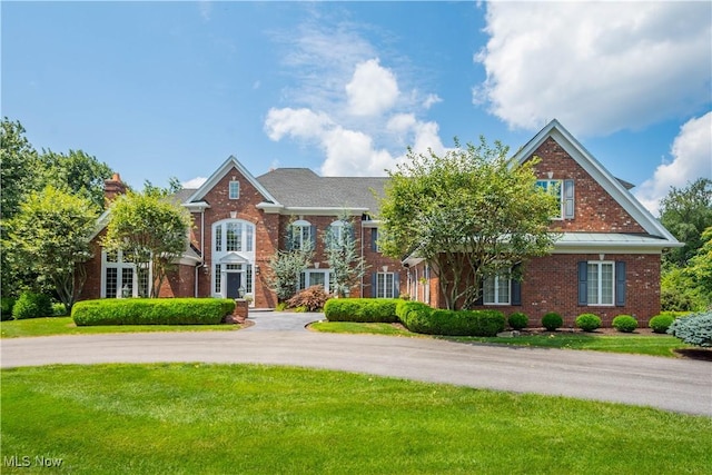 view of front of property with brick siding, a chimney, and a front yard