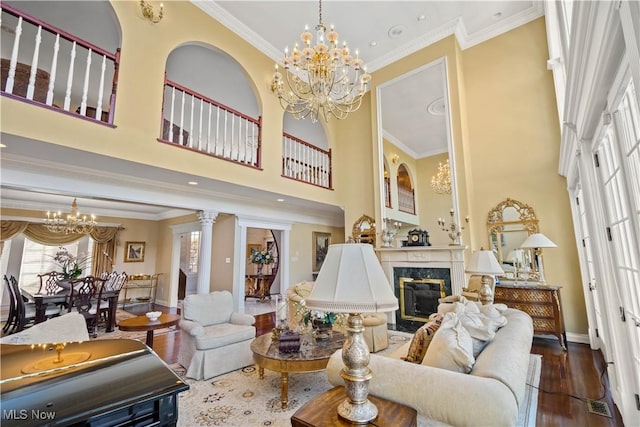 living room featuring wood finished floors, baseboards, a high ceiling, a notable chandelier, and a premium fireplace