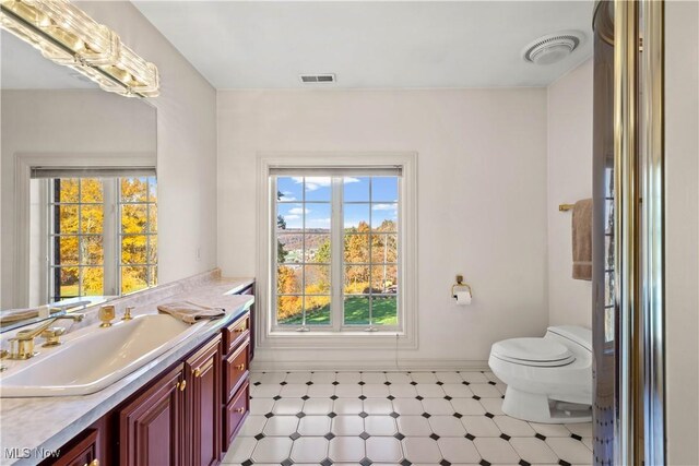 bathroom with vanity, toilet, tile patterned floors, baseboards, and visible vents