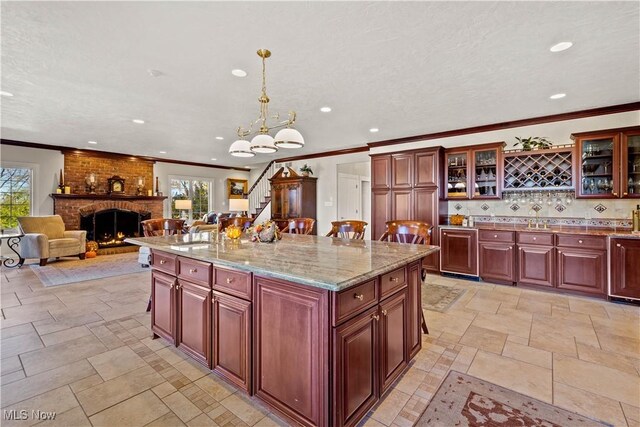 kitchen with reddish brown cabinets, a sink, a fireplace, and recessed lighting